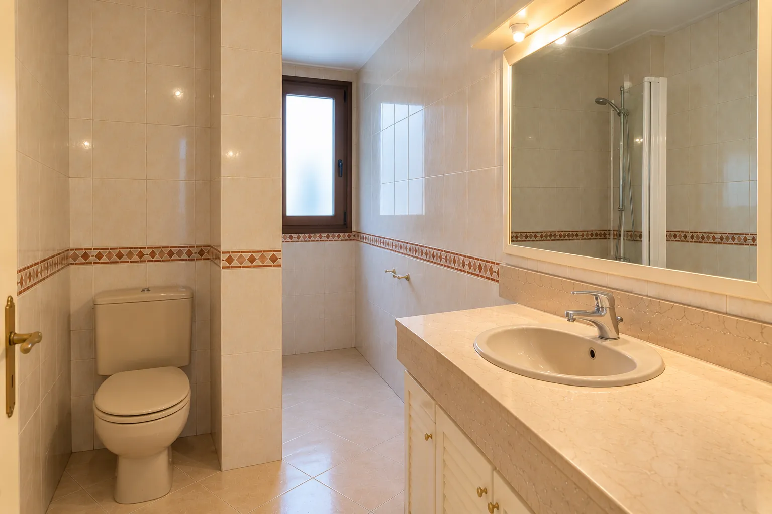 El baño antes: inodoro de tanque, ducha al fondo junto a la ventana y mueble de lavabo con puertas de lamas